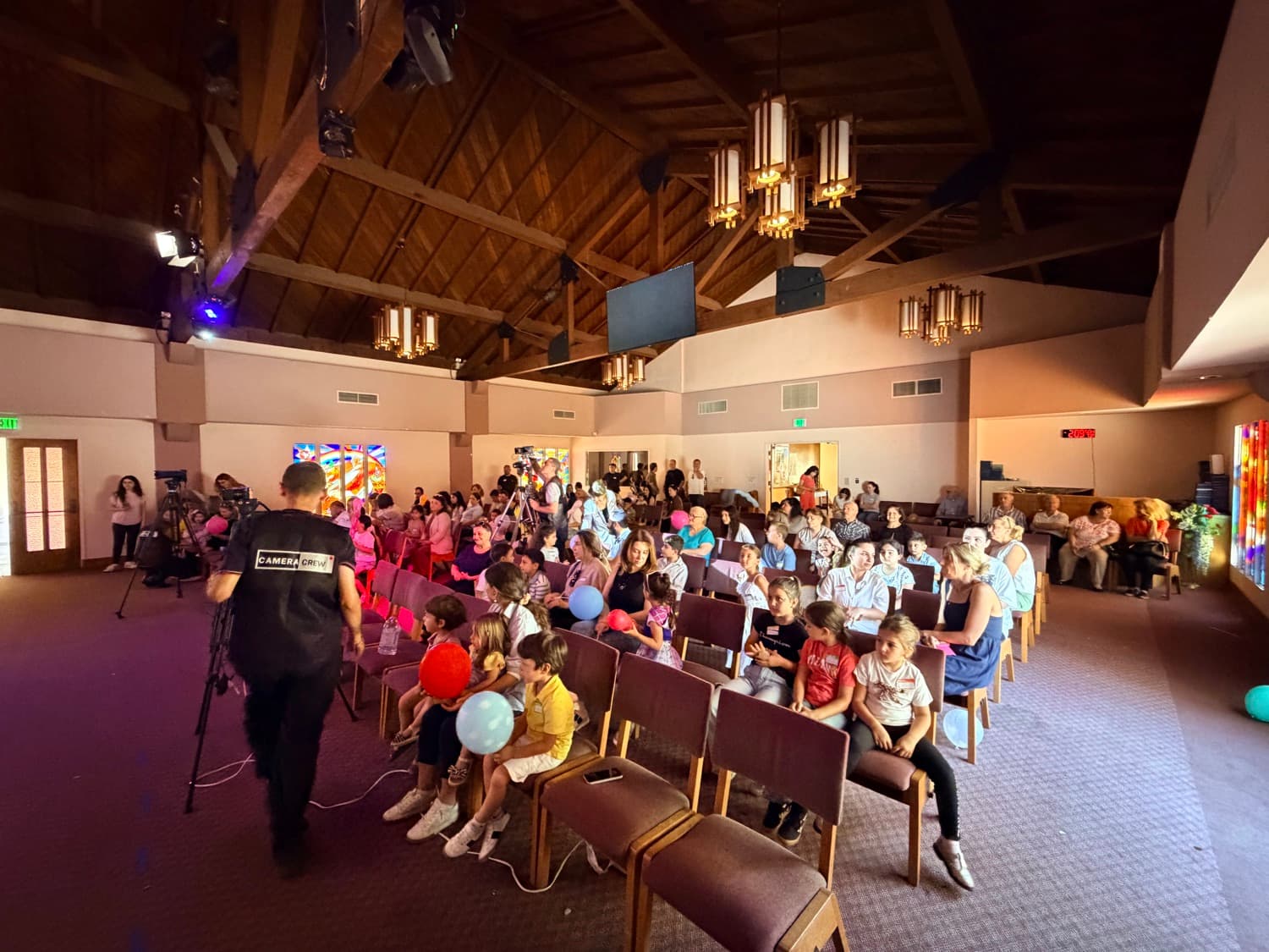 The hall watching — children in the front rows with balloons